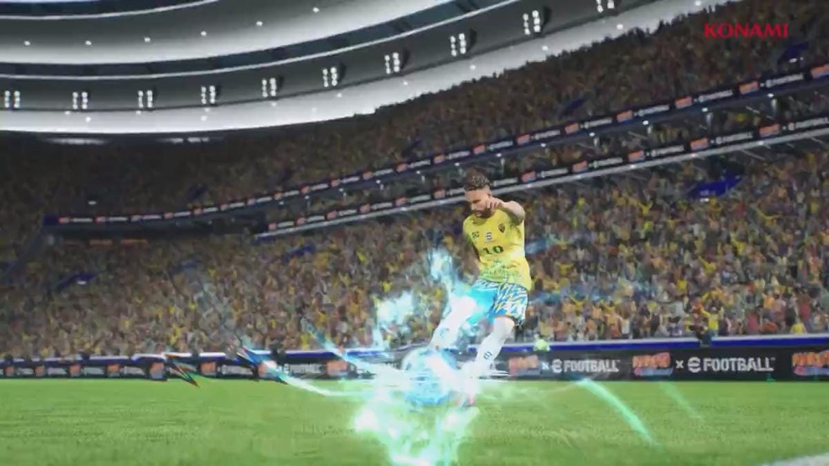 Pemain sepak bola dalam game eFootball menendang bola dengan efek energi biru bercahaya di stadion penuh penonton.