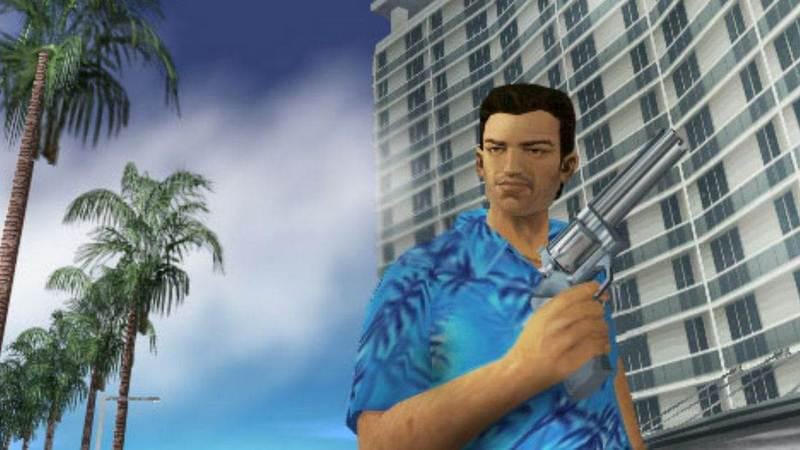 Karakter pria dalam permainan video era 2000-an mengenakan kemeja biru bermotif sambil memegang pistol di depan gedung tinggi dan pohon palem.